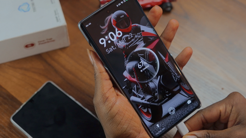 A person holding a Tecno Camon 40 Pro 4G smartphone displaying a motorcycle-themed lock screen, with a charging cable plugged in.