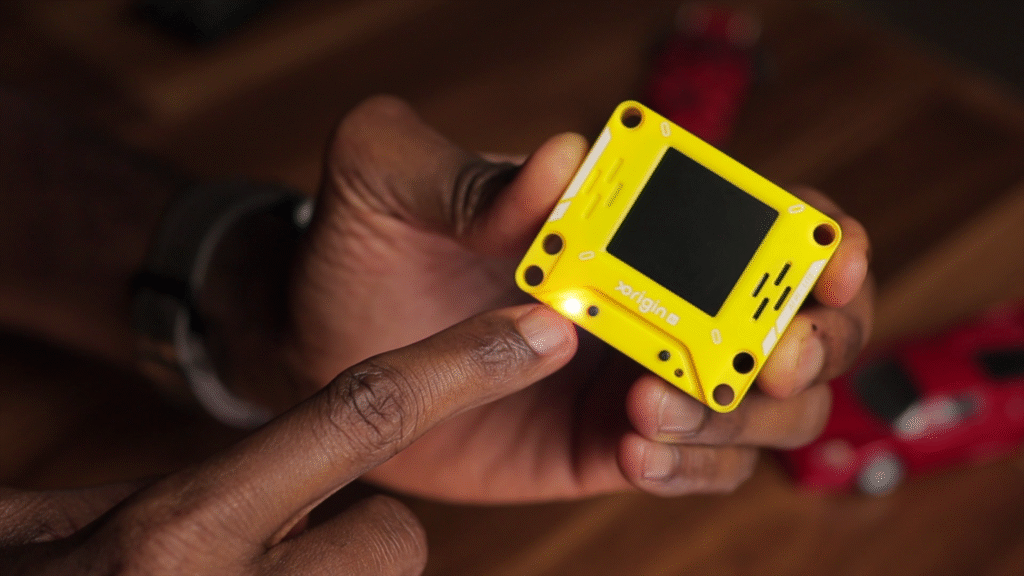 X-Origin AI PI Lite compact AI device with 128x128 display on desk with magnetic battery attachment