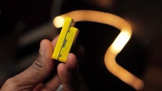 Hand holding X-Origin AI PI Lite smart assistant device demonstrating compact size and screen interface